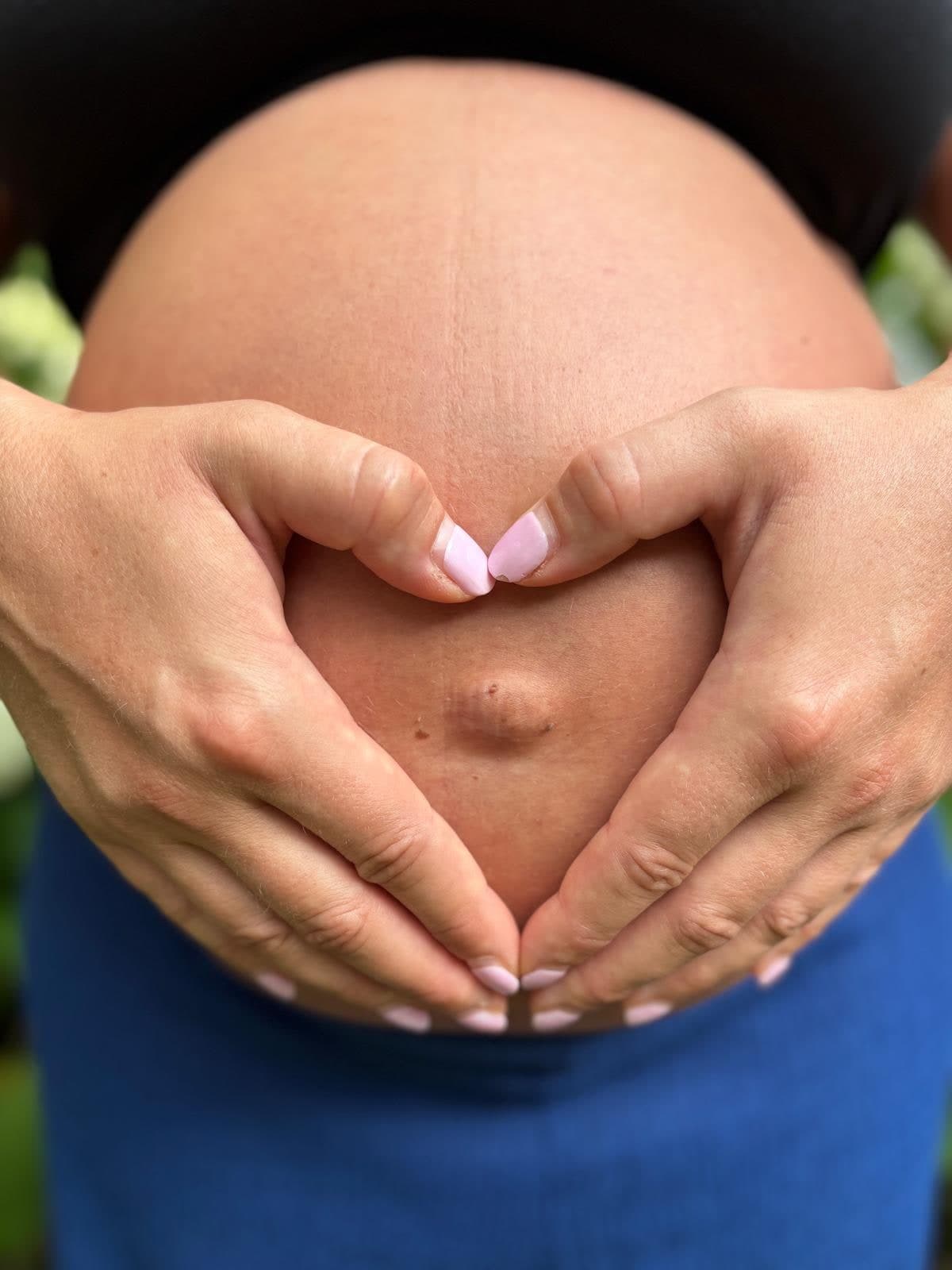 Deux mains formant un cœur sur un ventre de femme enceinte